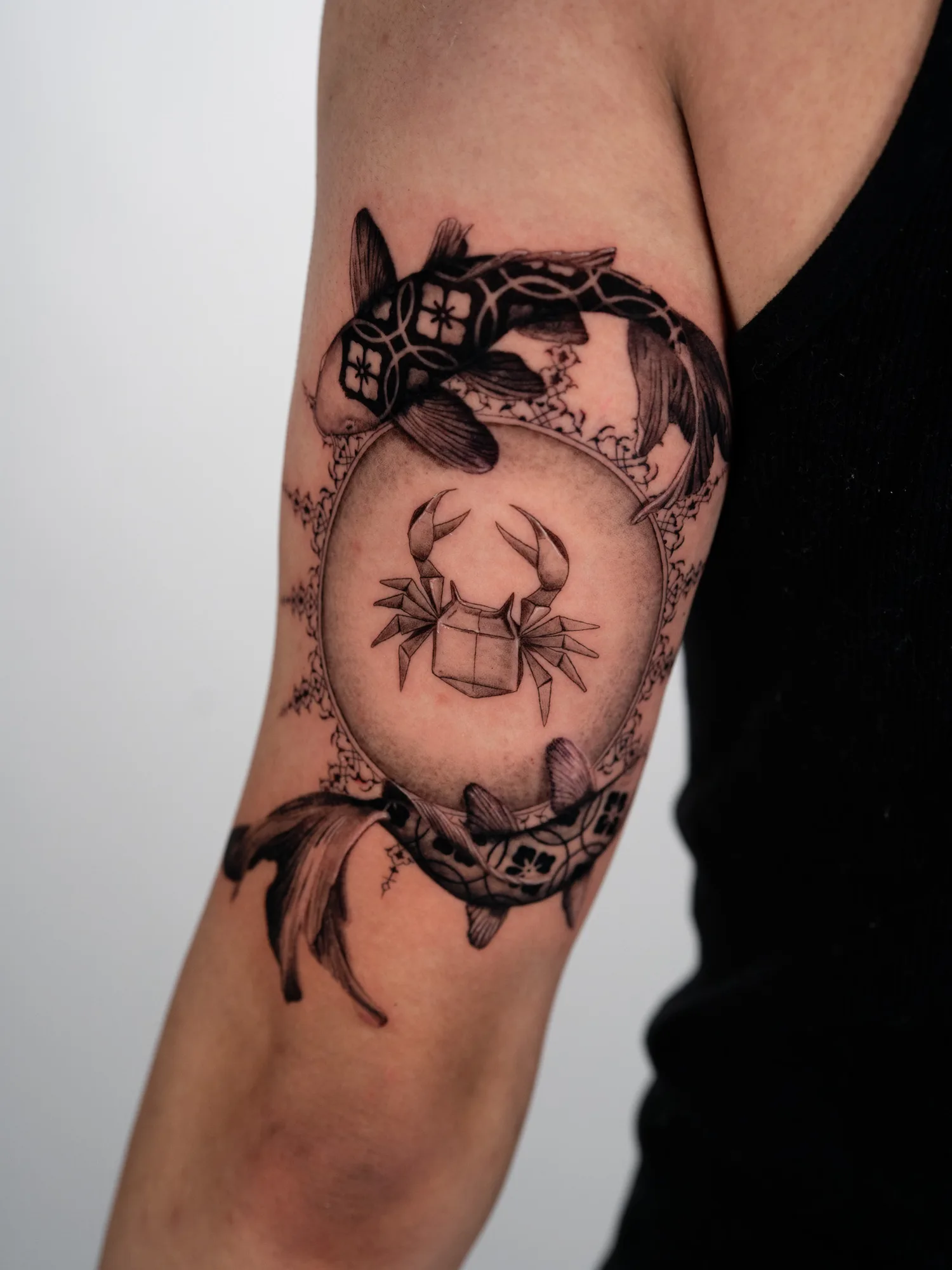 Tattoo of koi fish circling a crab on upper arm.