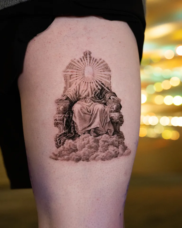 Tattoo of a robed figure on a throne with a radiant face