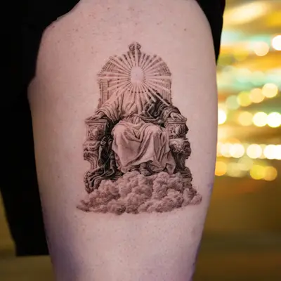 Tattoo of a robed figure on a throne with a radiant face