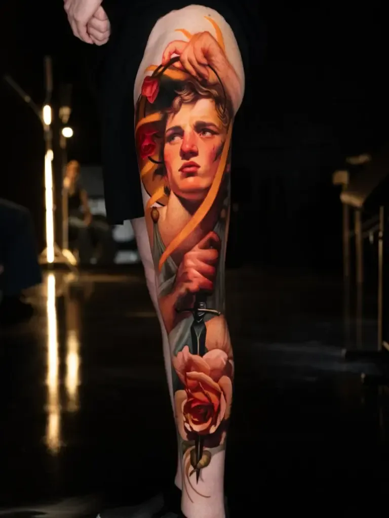 Tattoo of a realistic portrait with flowers on a leg