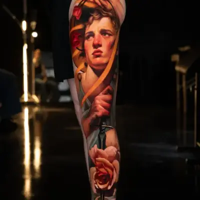 Tattoo of a realistic portrait with flowers on a leg