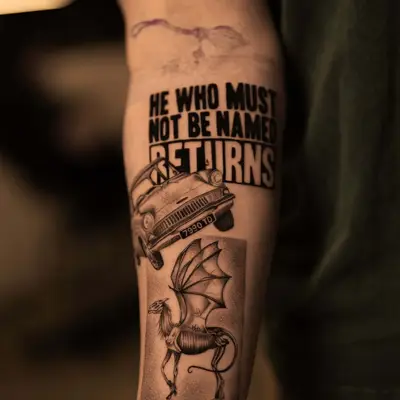 Tattoo of a phrase, car, and mythical winged creature on forearm.