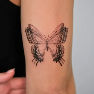 Detailed black and grey butterfly tattoo on forearm.
