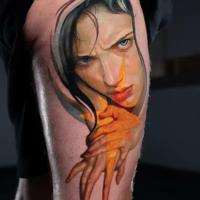 Surreal tattoo of a woman's face with geometric shapes on thigh.