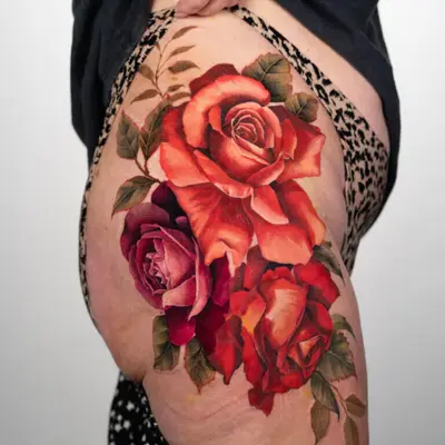 Colorful realistic rose tattoo on upper thigh.