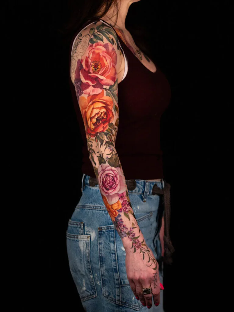 Colorful floral sleeve tattoo on woman's arm.