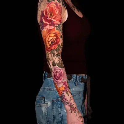 Colorful floral sleeve tattoo on woman's arm.