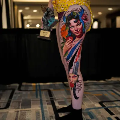 Colorful tattoo on leg with woman's face and apple.