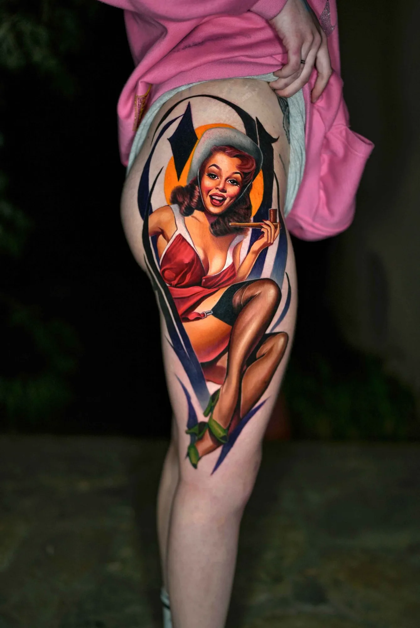 Colorful pin-up style tattoo on thigh featuring a woman in retro attire.