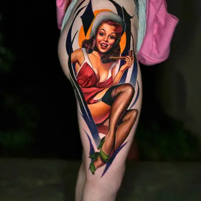 Colorful pin-up style tattoo on thigh featuring a woman in retro attire.