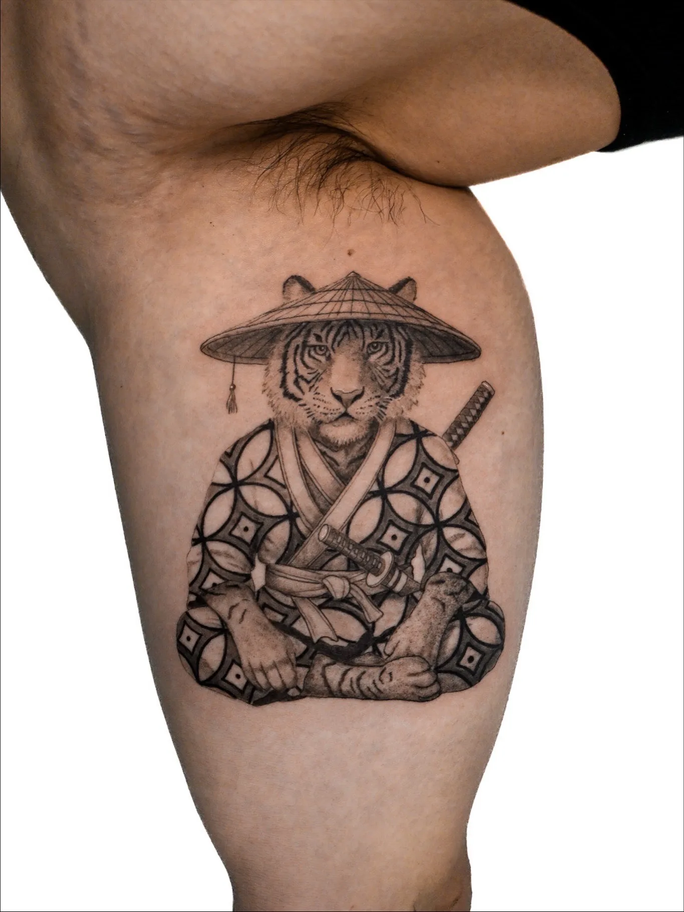 Tattoo of tiger in kimono with hat and sword on thigh.