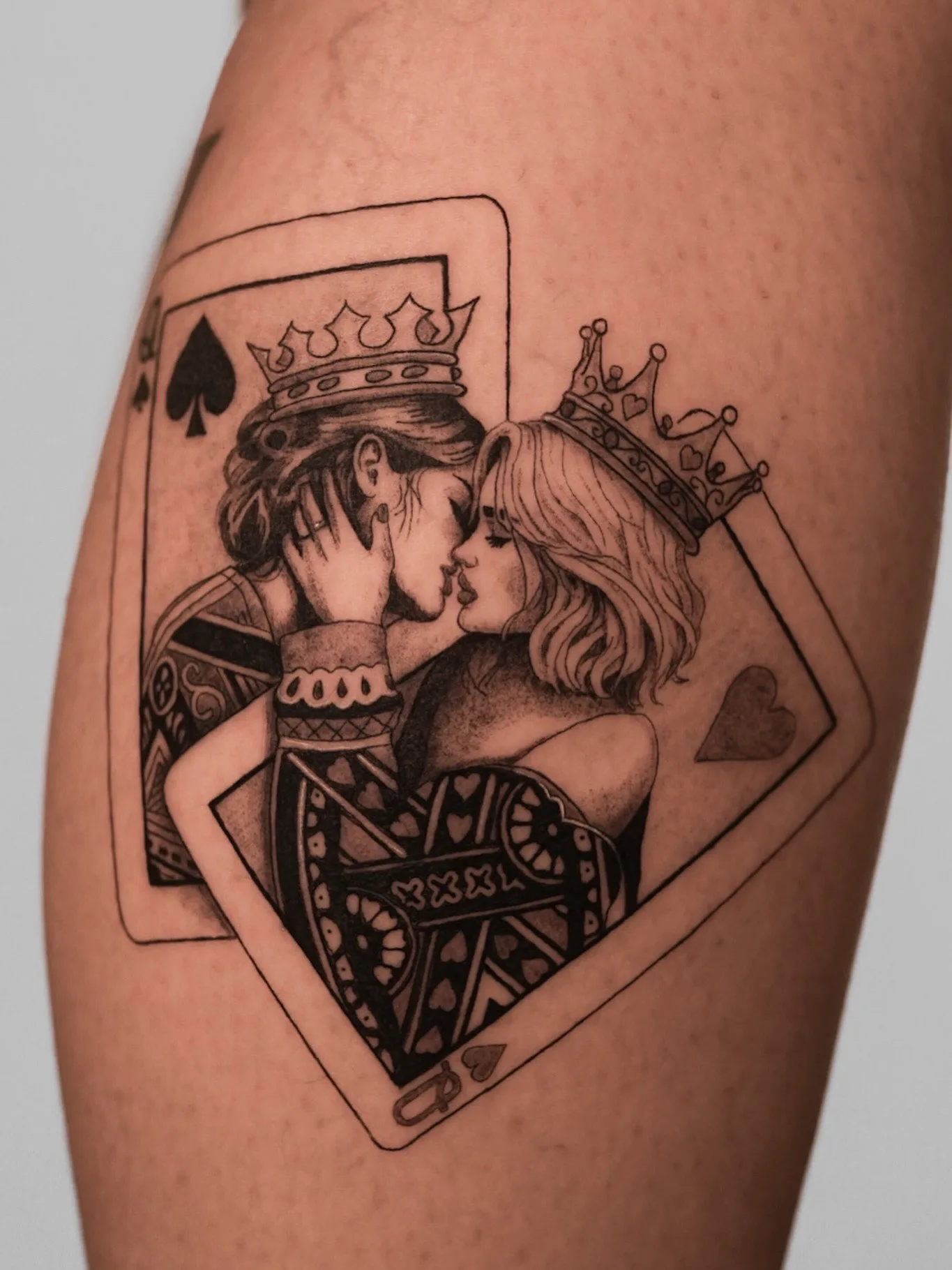 Tattoo of a king and queen kissing inside playing card frames.