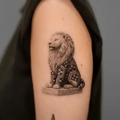 Tattoo of a lion with geometric patterns on upper arm.