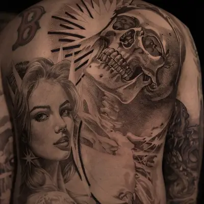 Tattoo of a woman's face and a skull on a man's back.