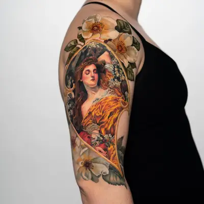 Colorful art nouveau style tattoo on upper arm with flowers and a woman.