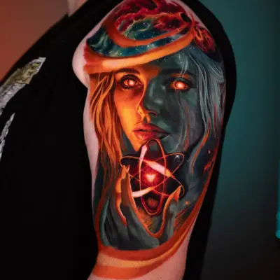 Colorful tattoo of a woman's face with cosmic elements on upper arm.