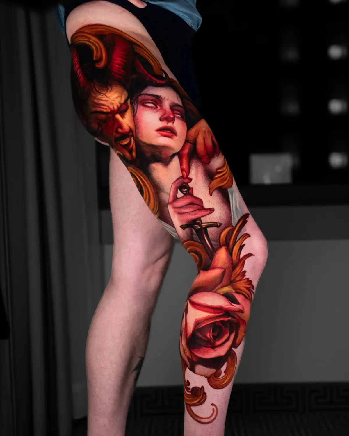 A vivid leg tattoo featuring a devil, a woman, and roses.