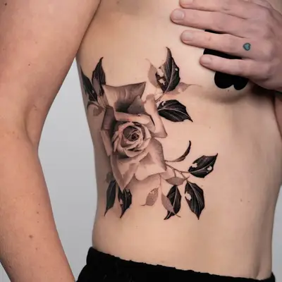Black and grey rose tattoo on ribcage