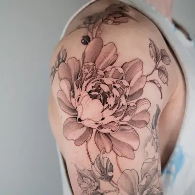 Black and grey floral tattoo on upper arm