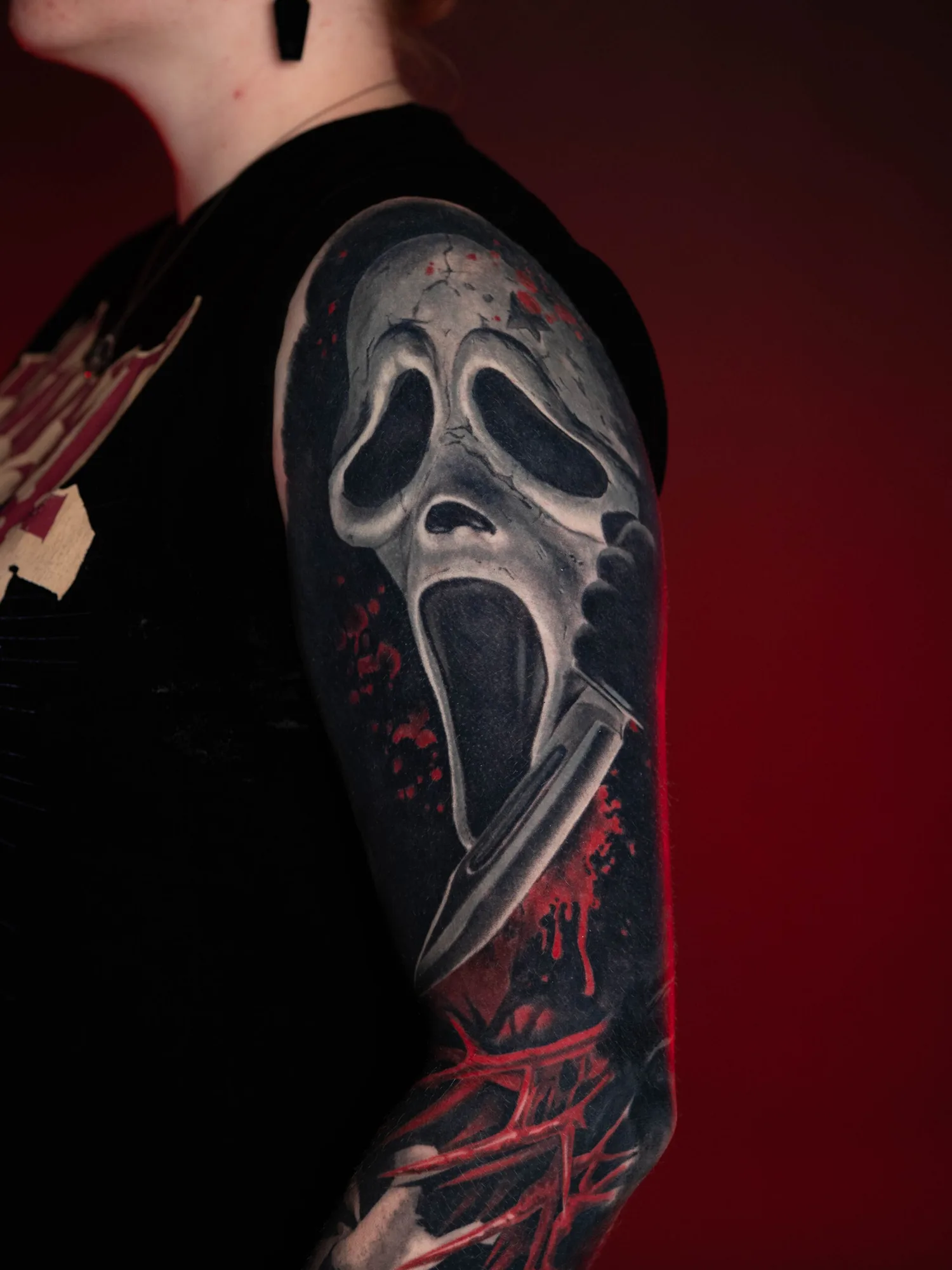 Tattoo of a horror mask with a knife on an arm sleeve