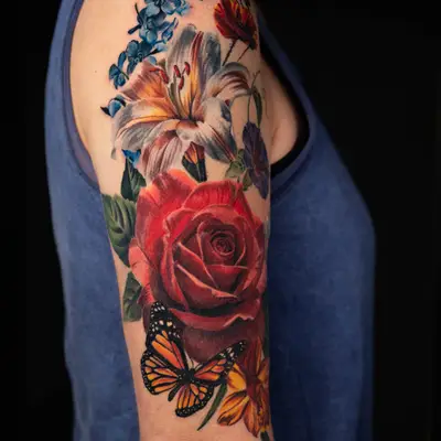 Colorful floral tattoo with roses and a butterfly on upper arm.