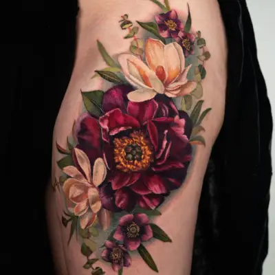 Realistic floral tattoo on thigh with roses and leaves.