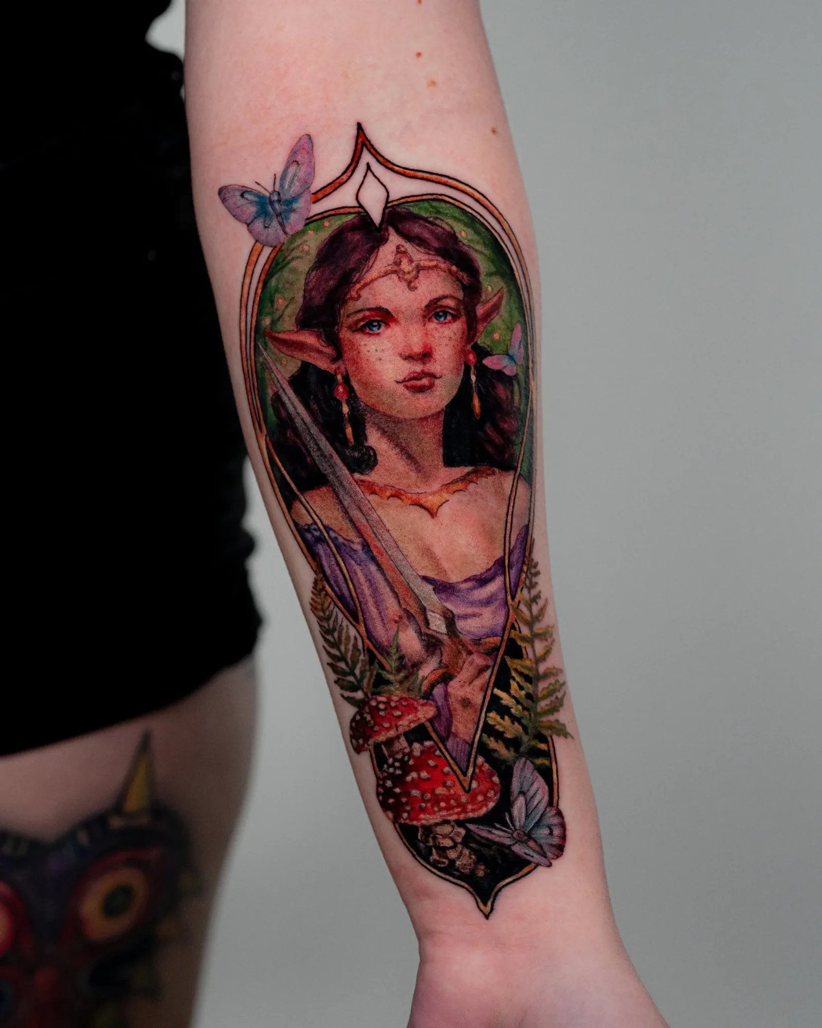 A painterly portrait on the inner forearm of an elvish lady in the forest with art nouveau framing.