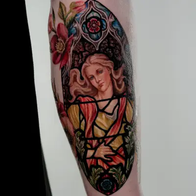 Colorful stained glass style tattoo of a woman with floral elements on the arm.