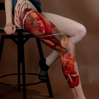 Tattoo of a woman's face with red hair and a rose on the leg.