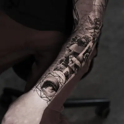 Black and grey full sleeve with a cherub, classical statue faces, handwritten script and a realistic eye set in a sacred geometry mandala at the wrist.