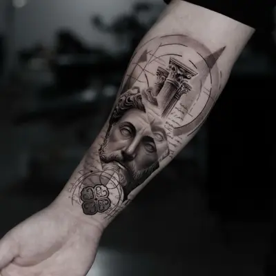 Black and grey forearm tattoo of a bearded marble bust below a Corinthian column capital, with geometric arcs and handwritten script.