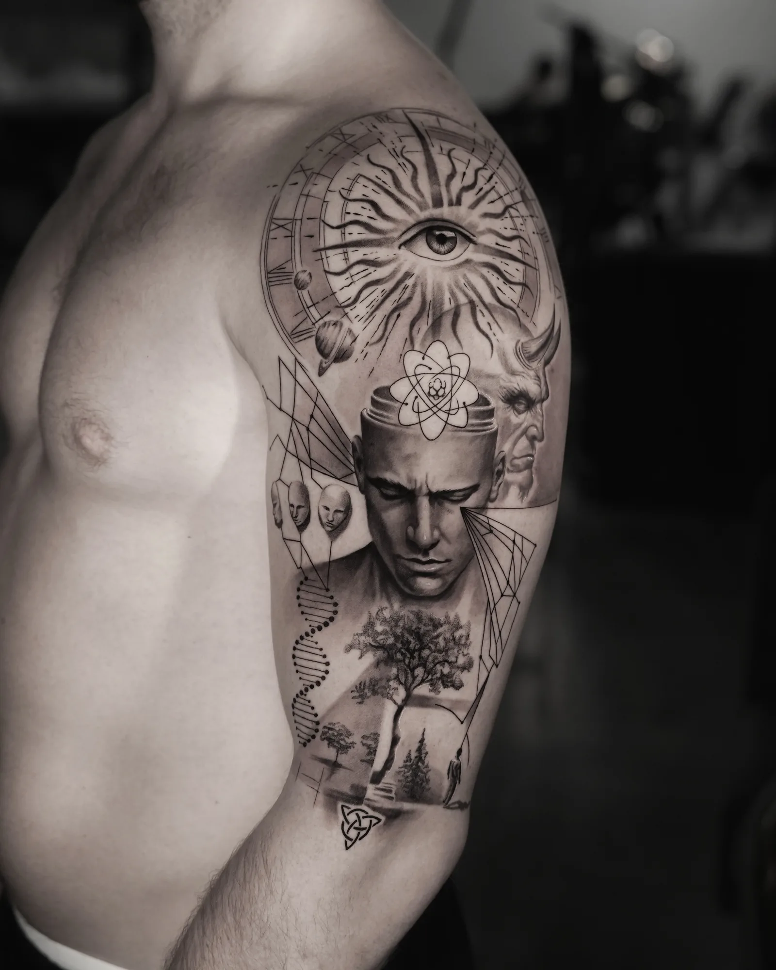 Black and grey half sleeve with a man's head opened at the crown, an all-seeing eye in a radiant wheel, a DNA helix, a tree and a horned figure.