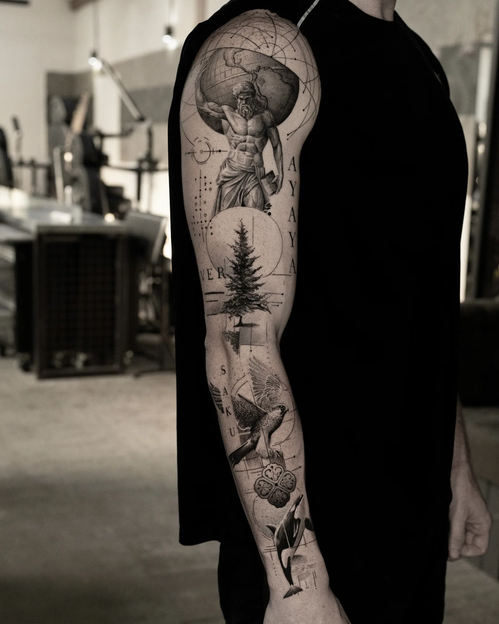 Black and grey full sleeve with Atlas holding the globe at the shoulder, a fir tree, a bird in flight, an ornamental rosette and an orca near the wrist.