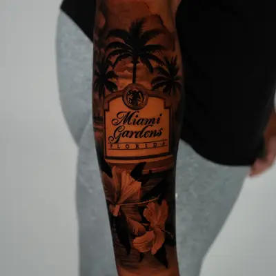 Miami Gardens Florida city sign with its municipal seal, framed by palm trees and hibiscus flowers, wrapping a forearm in black and grey.