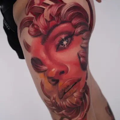 Color realism tattoo on the upper thigh: Selena Gomez portrait in deep reds and pinks framed by curling chrysanthemum petals in place of hair, with a starburst highlight in her eye.