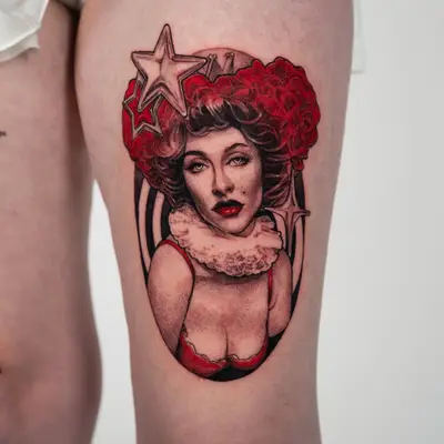 Fusion portrait tattoo on the thigh of Qveen Herby with a tall red curled updo, a small crown, a lace ruff and a red bodice, framed in a dark oval with glossy chrome stars.