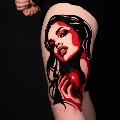 Tattoo of a woman with an apple on the thigh, in black and red shades.