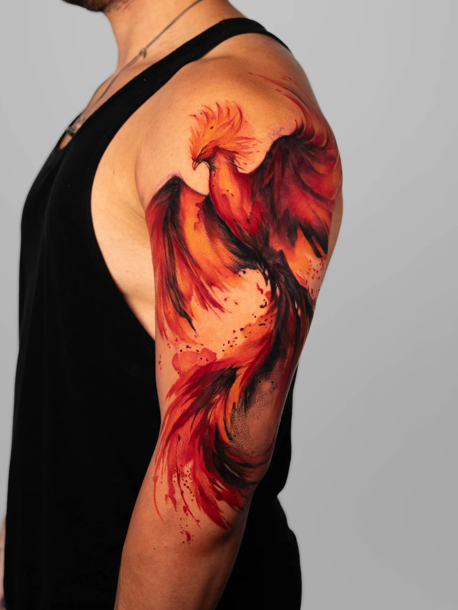 Phoenix tattoo in watercolor style on upper arm