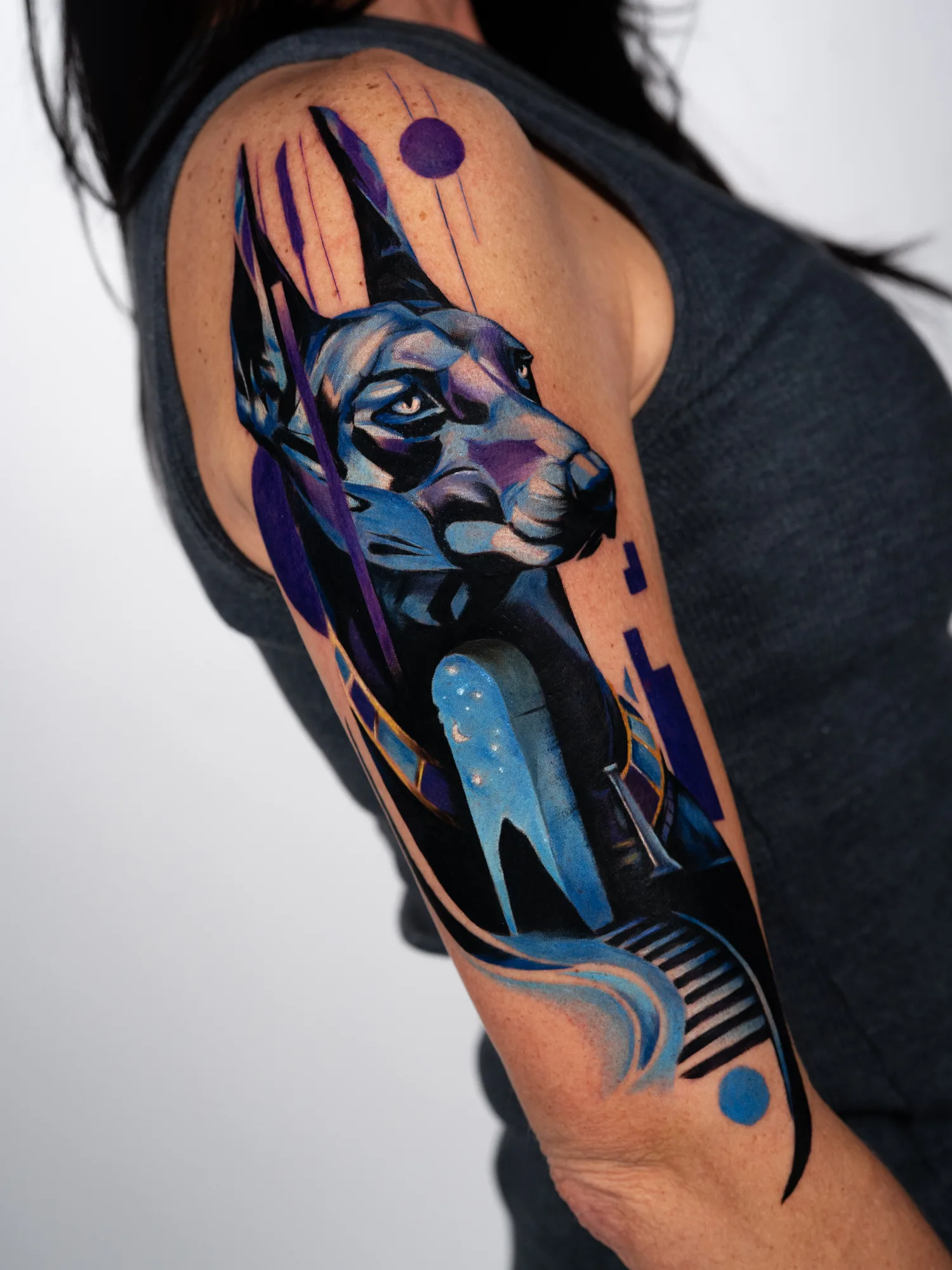 Tattoo of a geometric blue and purple dog with abstract elements.