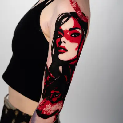 Tattoo of a woman's face with a red and black wolf on upper arm.