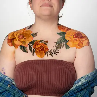 Vibrant floral tattoos on shoulders featuring yellow roses and green leaves.
