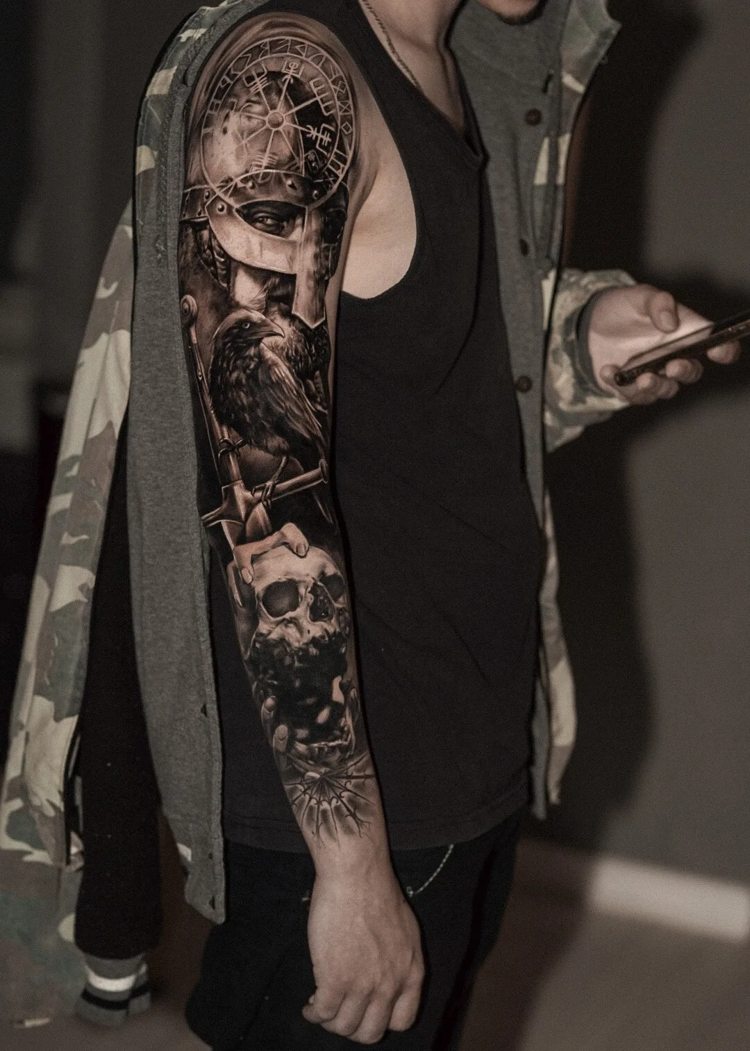Detailed black and grey tattoo sleeve with a Viking helmet, raven, and skull.
