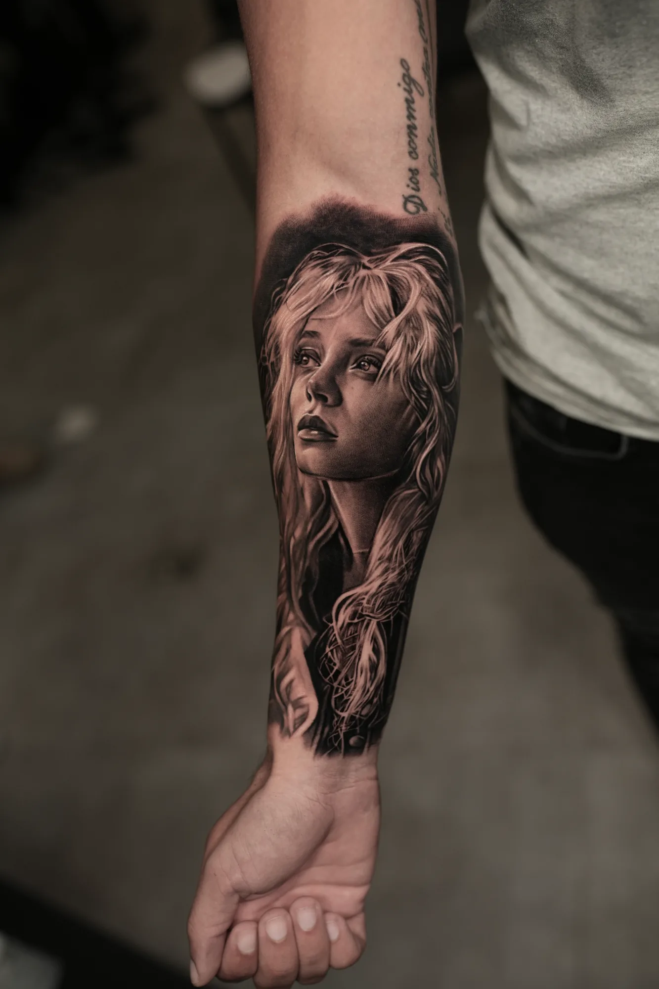 Realistic tattoo of a woman's portrait on a forearm.
