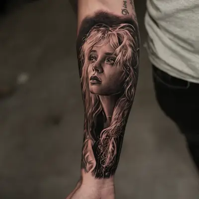 Realistic tattoo of a woman's portrait on a forearm.