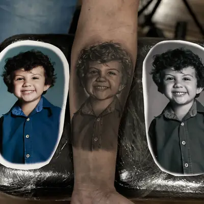 Black and grey portrait tattoo of a young child on forearm.