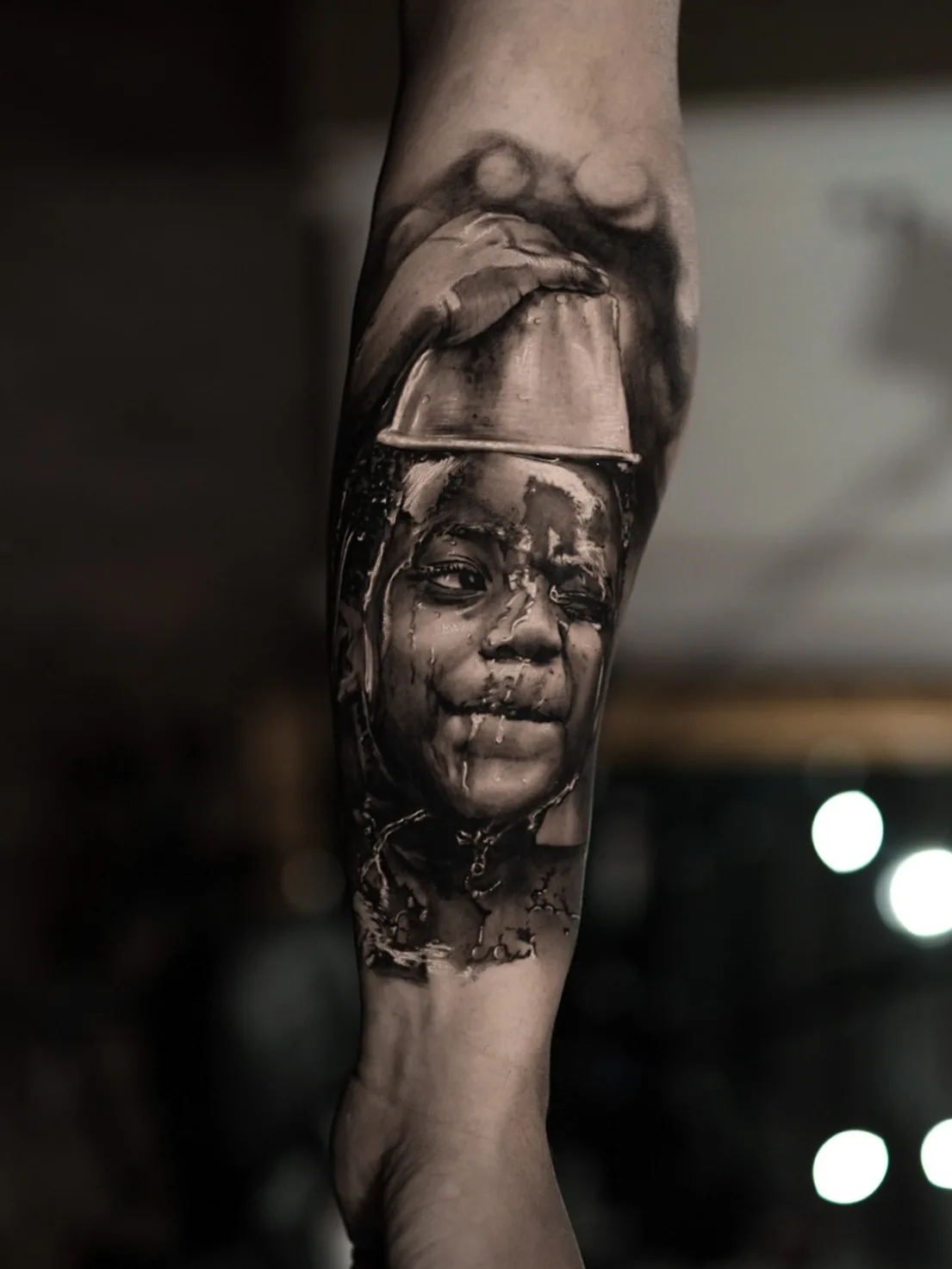 Black and grey portrait tattoo of a child with water splashes.