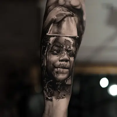 Black and grey portrait tattoo of a child with water splashes.