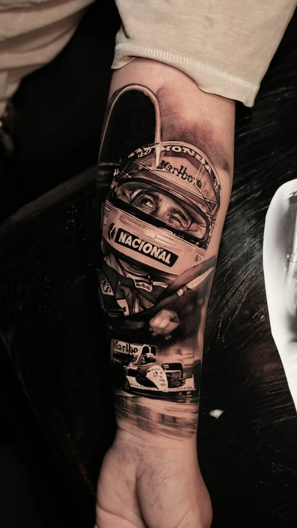 Realistic tattoo of a racing driver and car on an arm.