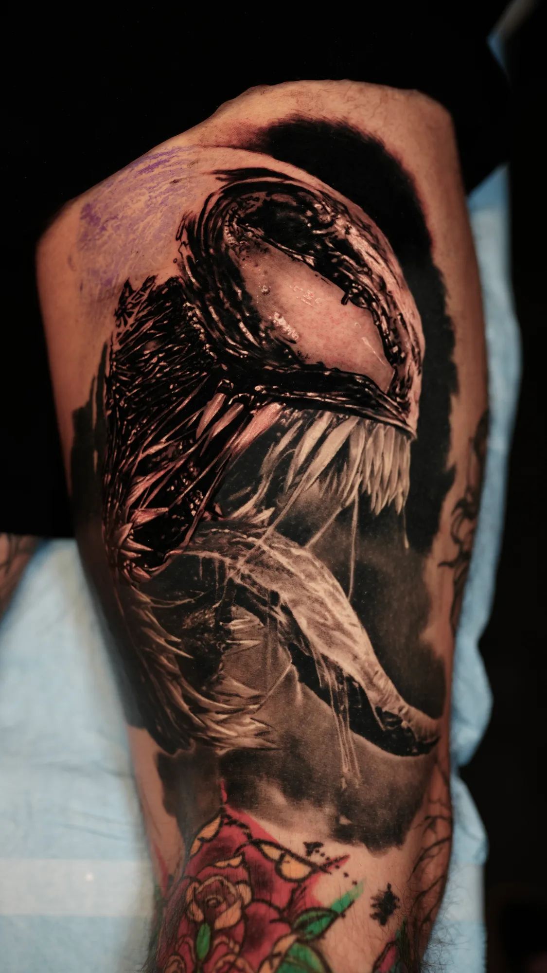 Black and grey tattoo of a fierce creature with sharp teeth.