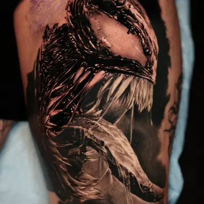 Black and grey tattoo of a fierce creature with sharp teeth.